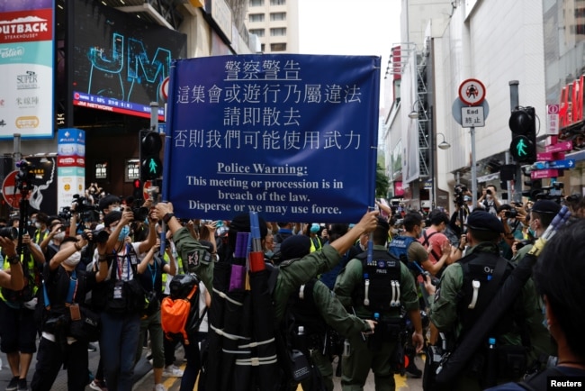 香港警察对在中国国庆日要求北京政府释放12港人的抗议者展示警示牌。（2020年10月1日）