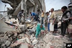 FILE - People sift through rubble of houses destroyed by Saudi-led airstrikes, in Sana'a, Yemen, Aug. 25, 2017.