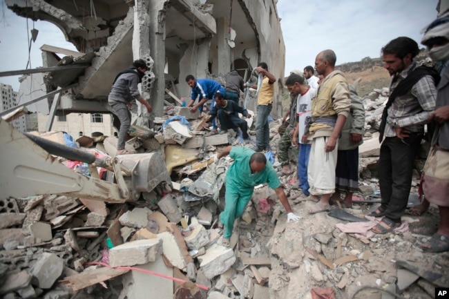 FILE - People sift through rubble of houses destroyed by Saudi-led airstrikes, in Sana'a, Yemen, Aug. 25, 2017.