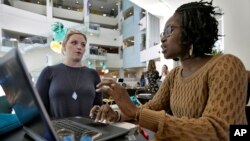 FILE - Xonjenese Jacobs, right, helps Kristen Niemi sign up for the Affordable Care Act in Tampa, Fla., Jan. 24, 2017. The Affordable Care Act’s fate is unclear. President Donald Trump has vowed to repeal it, but lawmakers have yet to reach an agreement o