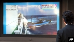FILE - A man watches a TV news showing a YouTube video which is said to be showing a collision between a Chinese fishing boat, right, and a Japanese coast guard vessel off disputed islands in Tokyo.