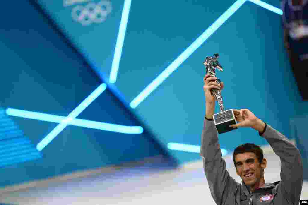 US swimmer Michael Phelps poses after receiving the trophy of the greatest olympic athlete of all time after winning gold in the men's 4x100m medley relay final during the swimming event at the London 2012 Olympic Games on August 4, 2012 in London. 