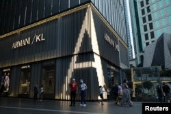 Sejumlah pengunjung melintas di depan toko Giorgio Armani di Kuala Lumpur, Malaysia, 27 Mei 2020. (Foto: Lim Huey Teng/Reuters)