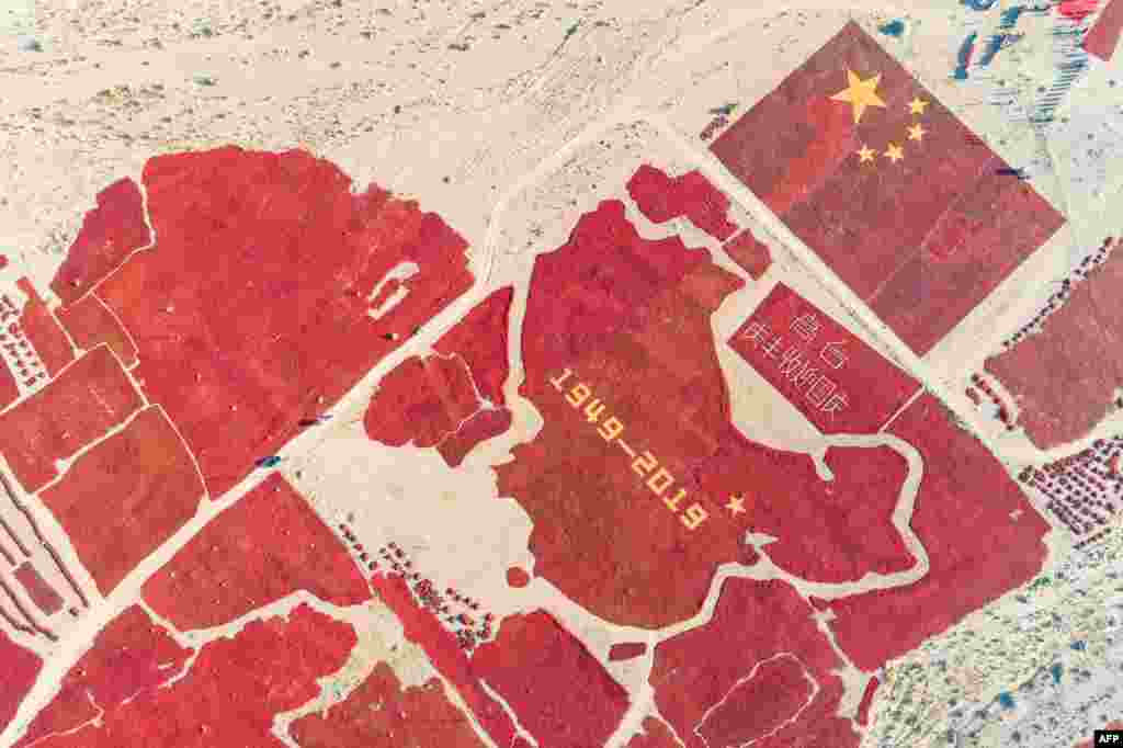 This aerial photo shows the image of a Chinese map and a national flag formed by dried chili peppers during the harvest season in Zhangye in China's northwestern Gansu province, as farmers celebrate the 70th anniversary of the founding of the People's Republic of China.