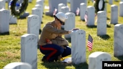 FILE - A female U.S. Marine touches the grave of a friend at Arlington National Cemetery in Virginia.