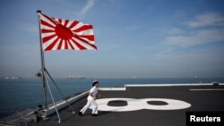 Yuma Osaki, a navigator, runs back to her post after a flag-raising ceremony on the flight deck of Japanese helicopter carrier Kaga before its departure for naval drills in the Indian Ocean, Indonesia, Sept. 22, 2018.