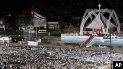 People attend a mass celebrated by Pope Benedict XVI in Antonio Maceo square in Santiago, Cuba, March 26, 2012.