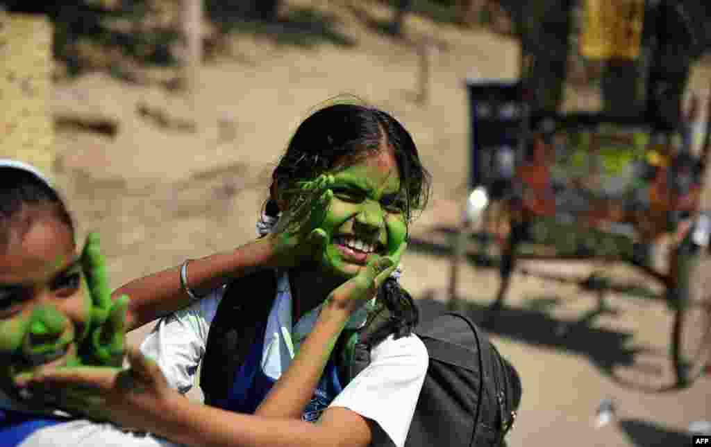 Dua siswa perempuan bermain dengan bubuk berwarna di luar sebuah sekolah di Allahabad, India. Warga India akan memperingati Festival Hindu Holi, yang tahun ini akan dirayakan 27 Maret.