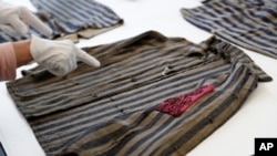 A conservator at the U.S. Holocaust Memorial Museum's conservation and research center points out a hidden pocket on a piece of clothing worn by a prisoner at a Nazi concentration camp.