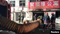 Firefighters work at the site of a house fire, in Daxing district, Beijing, early Nov. 19, 2017.