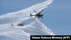 This handout photo taken and released by the Taiwan Defence Ministry on July 2, 2020 shows two US-made AH-64E attack helicopters releasing flares during a drill in Taichung. (Taiwan Defence Ministry/AFP)