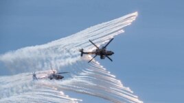 This handout photo taken and released by the Taiwan Defence Ministry on July 2, 2020 shows two US-made AH-64E attack helicopters releasing flares during a drill in Taichung. (Taiwan Defence Ministry/AFP)