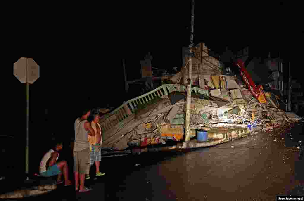 Residents wait in the streets next to a collapsed building after a 7.8 magnitude earthquake hit Ecuadoran northern coastal region, in the town of Pedernales, Ecuador, April 17, 2016.