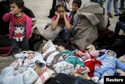Five Syrian babies, three of them triplets, lie on blankets among relatives following the arrival of migrants from the islands of Lesbos and Chios at the port of Piraeus, near Athens, Greece, Oct. 21, 2015.