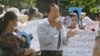 Rong Chhun, center, President of the Cambodian Trade Union Confederation, uses a megaphone during a protest near the prime minister's residence in Phnom Penh, Cambodia, Wednesday, July 29, 2020. (AP Photo/Heng Sinith)