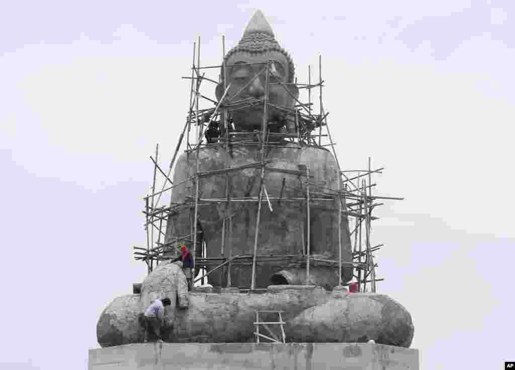 Para pekerja merenovasi patung Buddha raksasa di candi Tapong Nok, provinsi Rayong, Thailand timur.