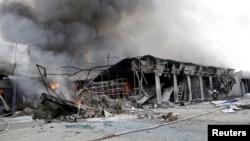 Một lính cứu hỏa đang dập lửa tại một khu chợ địa phương đã bị phá hủy do bị trúng pháo ở Donetsk, Ukraine, 3/6/2015.