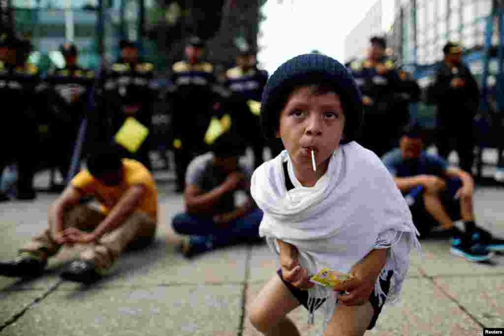 A migrant boy from Central America, moving in a caravan through Mexico, sucks a lollipop during a demonstration outside the U.S. Embassy in Mexico City, Mexico.