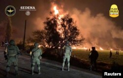 FILE - Military personnel watch as flames engulf an area after a ruptured fuel pipeline exploded, in the municipality of Tlahuelilpan, Hidalgo, Mexico, near the Tula refinery of state oil firm Petroleos Mexicanos (Pemex), Jan. 18, 2019.