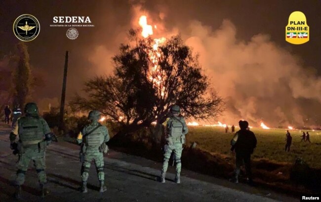FILE - Military personnel watch as flames engulf an area after a ruptured fuel pipeline exploded, in the municipality of Tlahuelilpan, Hidalgo, Mexico, near the Tula refinery of state oil firm Petroleos Mexicanos (Pemex), Jan. 18, 2019.