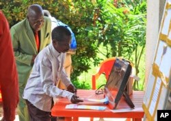 In this photo taken Oct. 16, 2018, a man demonstrates using an electronic voting machine that will be used later in the year for the next election in Beni, Eastern Congo.