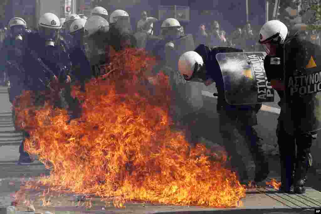 Protesters throw gas bombs at riot police officers during a 24-hour nationwide general strike in Athens, Greece, October 18, 2012.