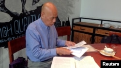 FILE - Xu Xiaoshun, the father of activism blogger Wu Gan, who was detained in what is known as the "709" crackdown, looks through documents about his son's case in a restaurant in Jiangsu Province, China, June 12, 2017.