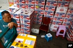 A man waits for the goods to be load on his tricycle at a dealer selling imported seafoods at the Jingshen seafood market in Beijing, Thursday, July 12, 2018.