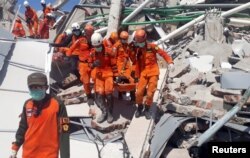 A search and rescue team evacuates a victim from the ruins of the Roa-Roa Hotel in Palu, Central Sulawesi, Indonesia, Sept. 30, 2018 in this photo taken by Antara Foto.