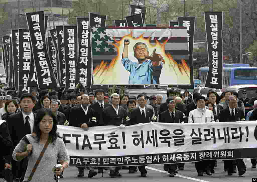 People march through the street during a funeral ceremony for Heo Se-uk, 56, the man who set himself ablaze in front of the venue for the South Korea-U.S. free trade agreement (FTA) talks. The banner reads: "South Korea-U.S. FTA talks are invalid! Raise H