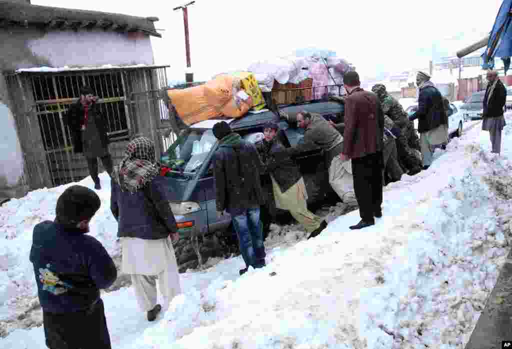 Afghan men push a car which became stuck near an avalanche site in Panjshir province north of Kabul, Feb. 25, 2015.