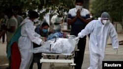 Zdravstveni radnici u Indiji prebacuju posmrtne ostatke žrtve Kovida 19, (Foto: Reuters/Amit Dave)