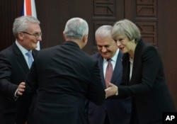 FILE - British Prime Minister Theresa May (R) talks to Temel Kotil (back on camera), CEO of Turkish Aerospace industries, as Turkey's Prime Minister Binali Yildirim (2nd-R) and Ian Graham King (L), CEO of BAE Systems, look on after signing an agreement i