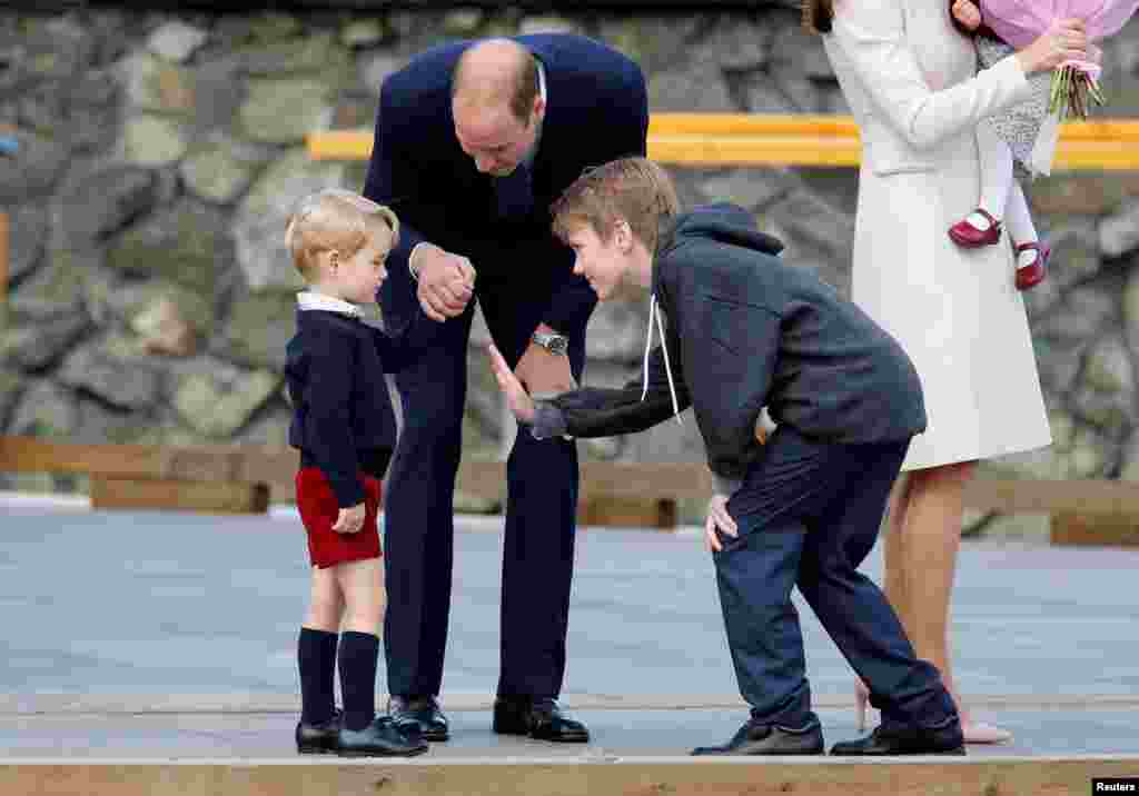 Daniel Bachman (R), who presented flowers to the Royal family, tries to high-five Britain&#39;s Prince George (L) while Prince William looks on as they arrive to board a floatplane for their official departure from Canada in Victoria, British Columbia, Canada, Oct. 1, 2016.