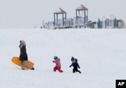Christina Mesavage leads family friend, Una Mayer, center, and her son, Jude, up a sledding hill at the Eastern Promenade while enjoying the snow, March 8, 2018, in Portland, Maine.