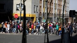 FILE - Stick-wielding protesters march through the streets as violence following the jailing of former South African President Jacob Zuma spread to the country's main economic hub in Johannesburg, South Africa, July 11, 2021.