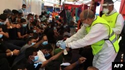 Un agent de santé italien donne des bracelets numérotés aux migrants secourus en mer sur le navire de sauvetage "Ocean Viking", exploité par l'ONG française SOS Méditerranée, le 5 juillet 2020.