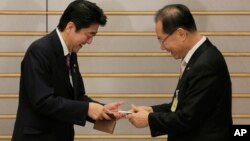 South Korea's ruling Saenuri Party chairman Hwang Woo-yea, right, and Japanese Prime Minister Shinzo Abe exchange their business cards prior to their meeting at the prime minister's residence in Tokyo, Wednesday, Jan. 9, 2013. (AP Photo/Itsuo Inouye, Pool)