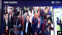In this photo taken Tuesday, Oct. 23, 2018, visitors are tracked by facial recognition technology from state-owned surveillance equipment manufacturer Hikvision at the Security China 2018 expo in Beijing, China. (AP Photo/Ng Han Guan)