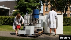 Ilmuwan Belgia Marjolein Vanoppen dan Sebastiaan Derese (kanan) menunjukkan cara menggunakan mesin bertenaga surya untuk mengubah air seni menjadi air minum dan pupuk di kampus University of Ghent, Belgia (26/7). (Reuters/Francois Lenoir)