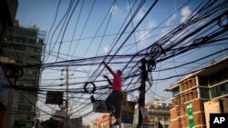 A Bangladeshi man works on the tangled electric cables hanging above a street in Dhaka, Bangladesh, Dec. 12, 2017. 