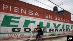 A cyclist rides past a mural for Eruviel Avila, candidate for governor of the state of Mexico for the Institutional Revolutionary Party (PRI) in Toluca, July 2, 2011