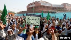 A supporter of the Tehreek-e-Labaik Pakistan, an Islamist political party, holds a sign, which reads in Urdu, "remove Zahid Hamid" during a sit-in protest along a main road in Karachi, Nov. 27, 2017.