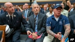 El comediante y activista Jon Stewart con bomberos, socorristas y sobrevivientes de los ataques terroristas del 11 de septiembre en una audiencia del Comité Judicial de la Cámara de Representantes, en el Capitolio, en Washington, el martes 11 de junio de 2019. 
