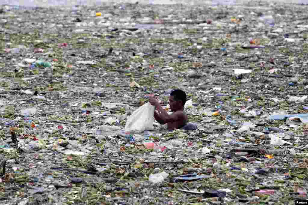A man collects plastic and other recyclable materials from debris in the waters of Manila Bay after tropical storm Saola hit the Philippine capital, July 30, 2012.