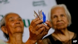 Narcisa Claveria, 85 (kiri), dan Hilaria Bustamante, 90, yang diduga lansia mantan wanita penghibur menunjukkan origami yang menunjukkan simbol perdamaian di wilayah suburban kota Quezon, timur laut kora Manila, Filipina (Foto: dok). 