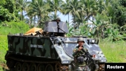 A government troop gestures as he passes an armoured personnel carrier posted along a main highway of Pantar town, Lanao Del Norte, after residents start to evacuate their hometown of Marawi city, southern Philippines, May 24, 2017.