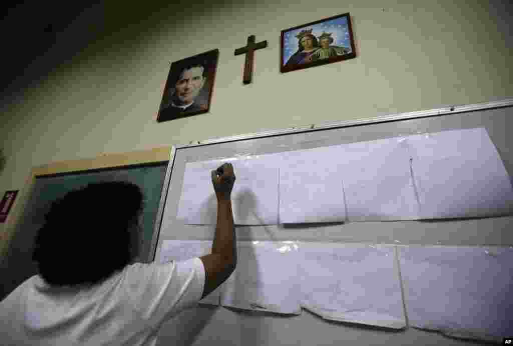 A polling station delegate writes down counted votes on a board at the San Francisco de Sales school in Caracas, April 14, 2013. 