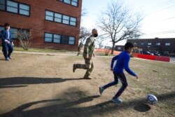 Afghan children play soccer with U.S. Air Force Tech. Sgt. Scott Nussel, a cultural awareness specialist, outside a temporary housing in Liberty Village on Joint Base McGuire-Dix- Lakehurst in Trenton, N.J., Dec. 2, 2021.