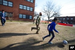 Afghan children play soccer with U.S. Air Force Tech. Sgt. Scott Nussel, a cultural awareness specialist, outside a temporary housing in Liberty Village on Joint Base McGuire-Dix- Lakehurst in Trenton, N.J., Dec. 2, 2021.